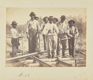 [Workers standing on railroad tracks]